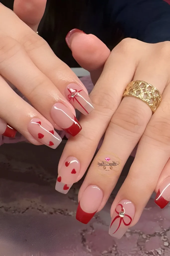 Square nails with red French tips, scattered red hearts, and red bow outlines with rhinestone centers.