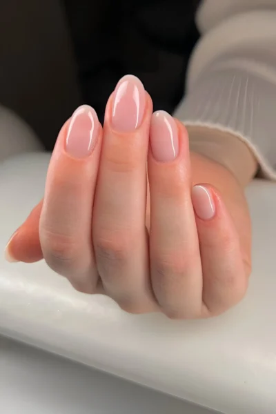 Short rounded nails with a sheer pink glossy finish embodying the Your Nails But Better clean girl look.