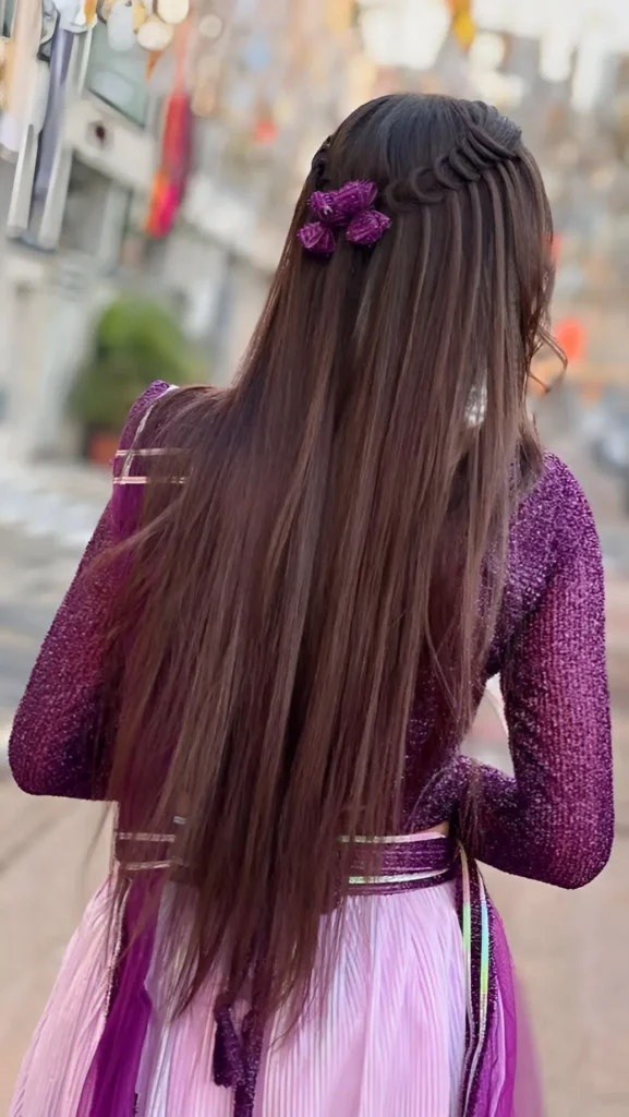 Back view of long, straight dark brown hair featuring a subtle waterfall braid accented with a purple floral clip on one side.