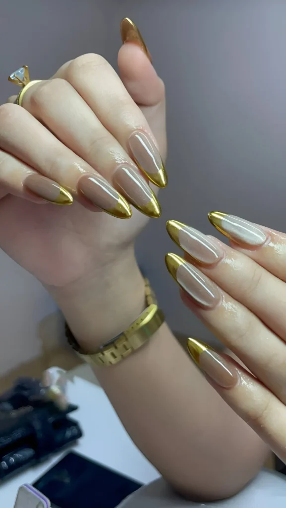 Pointed almond nails with a semi-opaque taupe base and full coverage metallic gold chrome French tips.