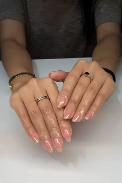 Medium-length almond nails with a sheer pinky-nude polish and glossy finish for a clean girl look.