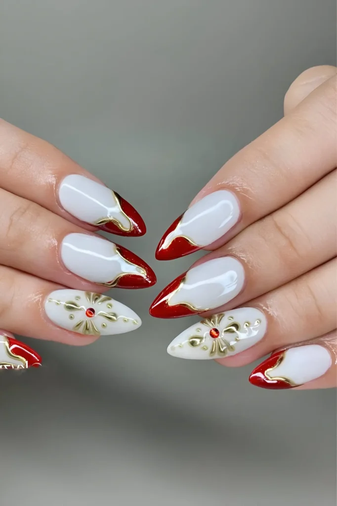 Pointed nails with white base, red tips, raised gold borders, and 3D gold filigree accents with red gems.