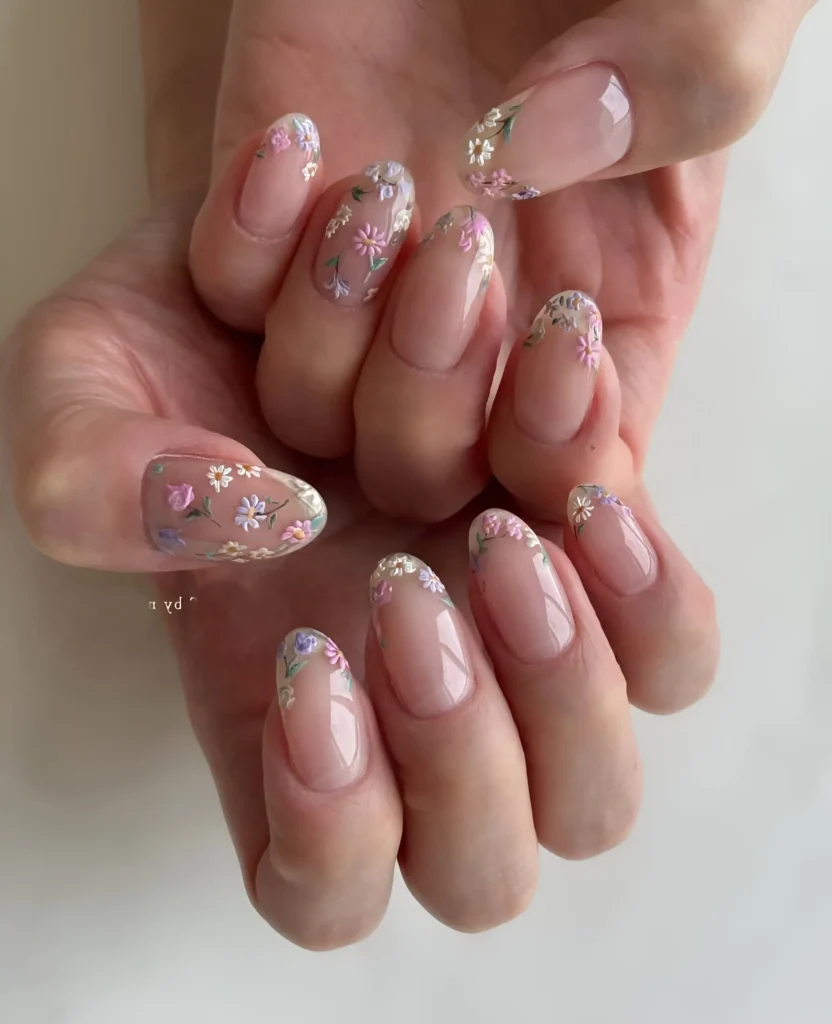 Delicate hand-painted micro-florals in pastel colors scattered over sheer nude almond nails.