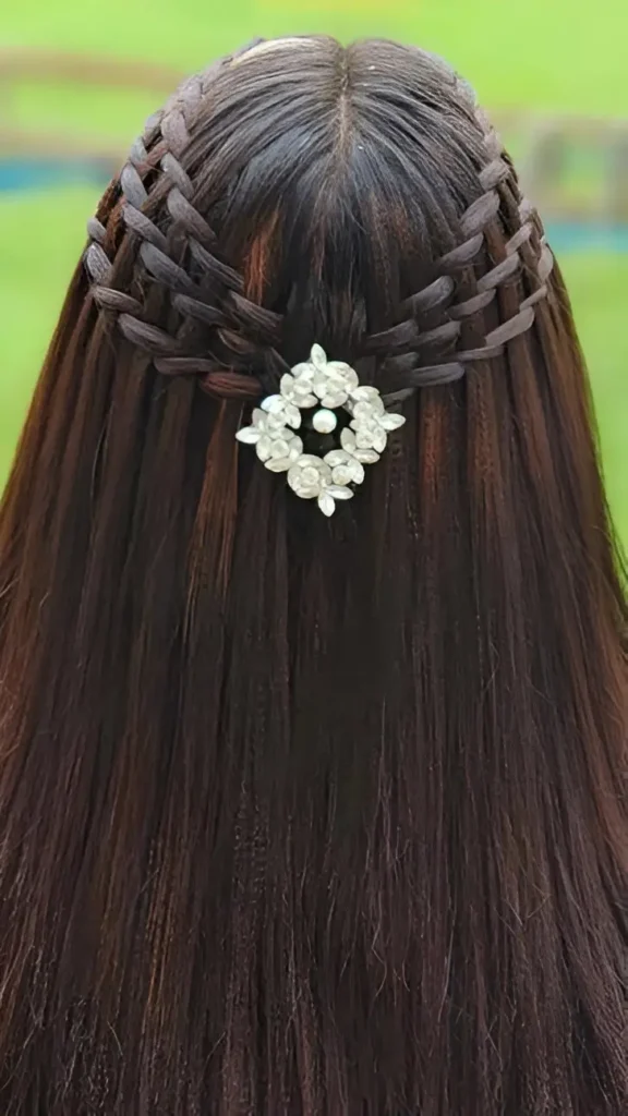 Close-up back view of long dark straight hair styled with an intricate basket weave braid pattern, accented by a central sparkly floral accessory.