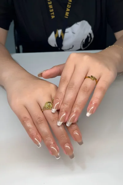 Long tapered square nails with a soft ombré French or baby boomer effect, blending sheer nude to white.