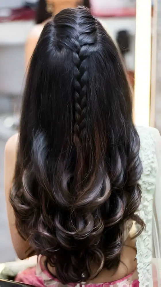 Back view of long dark hair with curled ends, featuring a single prominent Dutch or French braid down the center parting.