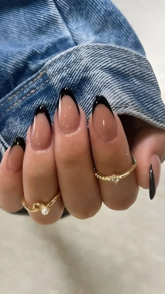 Almond-shaped nails with a classic French manicure featuring glossy black tips and a sheer nude base.