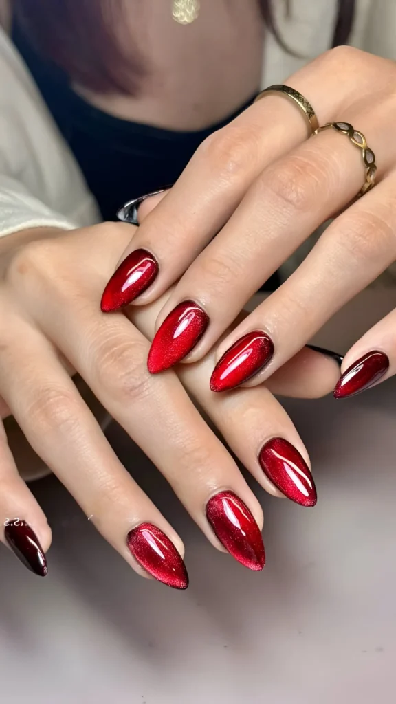 Almond nails with a deep red velvet cat eye magnetic polish effect.