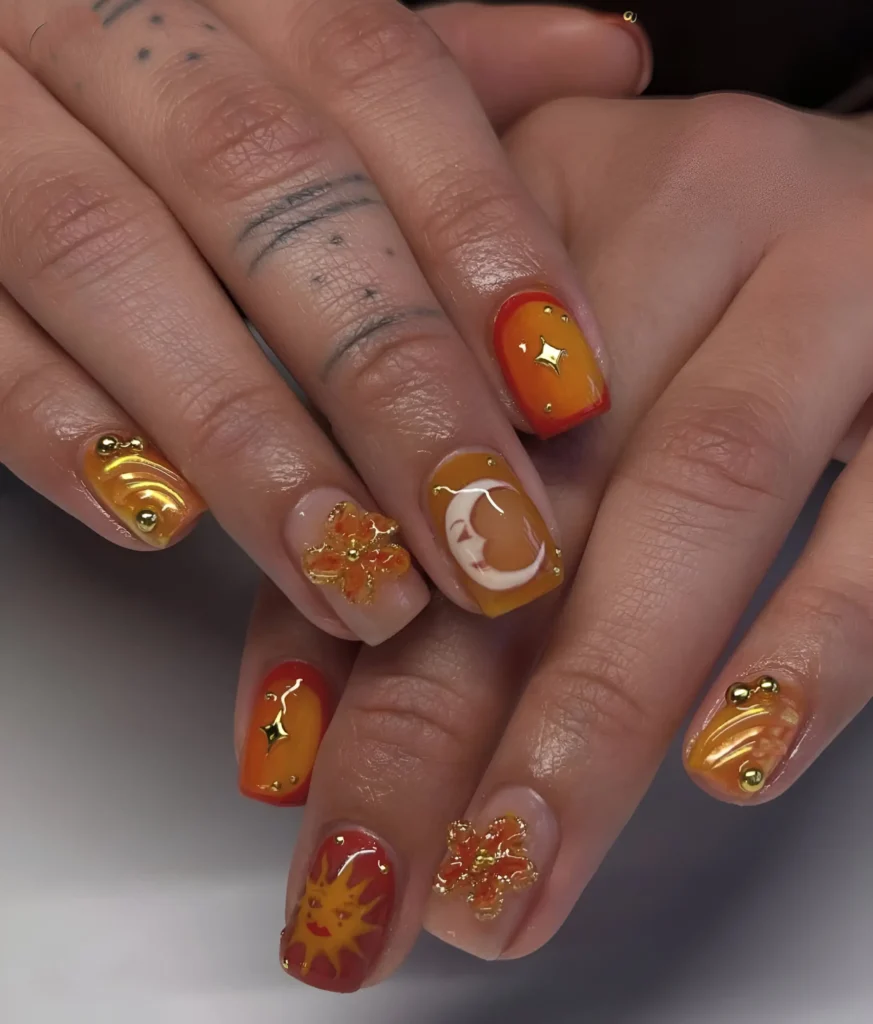 Warm celestial nail art featuring painted sun and moon motifs, textured swirls, and gold charms on short square nails.