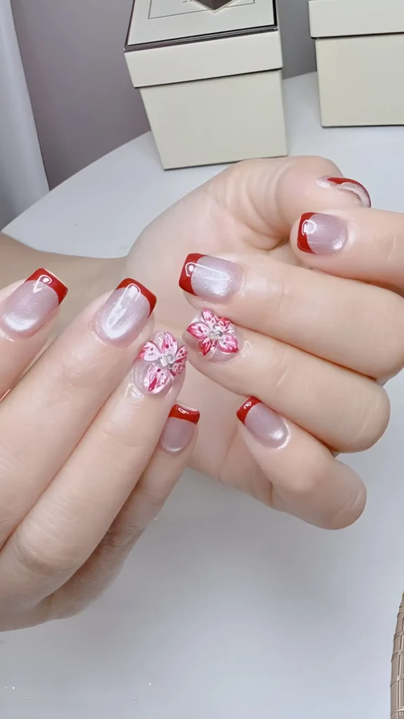 Squoval nails with vibrant red French tips and intricate 3D sculpted pink flower accents, an elegant classy nail design.