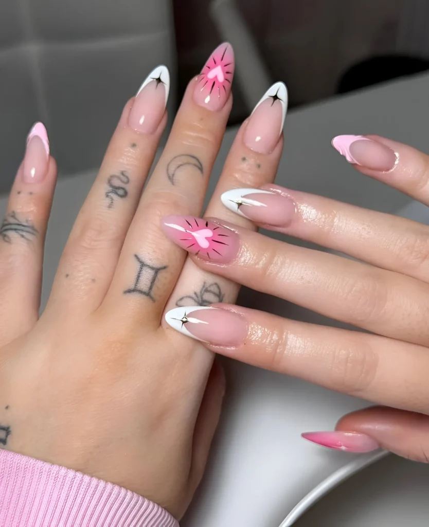 Modern manicure mixing pink and white French tips with graphic black heart bursts and sparkle accents.