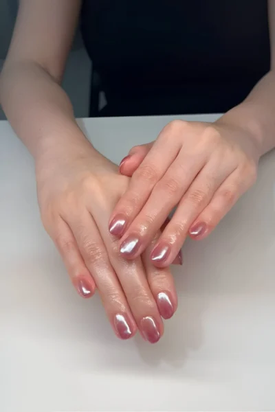 Short rounded nails with a luminous glazed donut effect, featuring a pearlescent chrome finish over a neutral base.