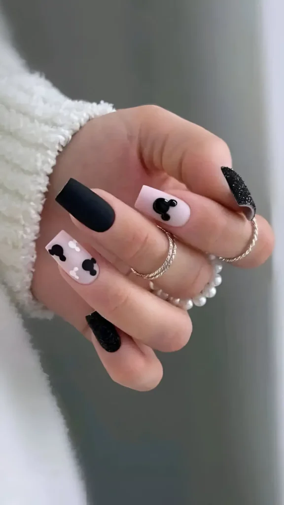 Long coffin nails with mixed textures: matte black, black glitter, and matte pink nails featuring a glossy black round silhouette with ears. Black Nail Designs