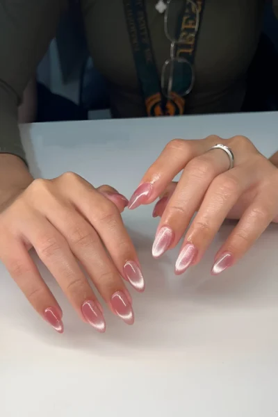 Almond nails with a sheer pink base featuring a diagonal silver cat eye or magnetic polish effect.