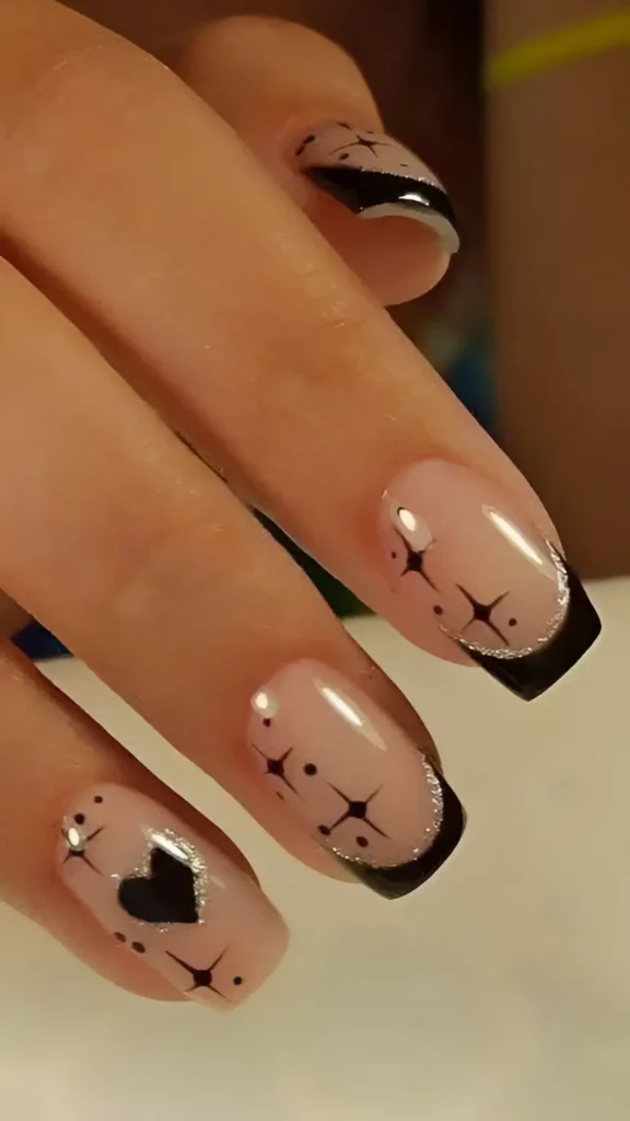 Square nails with black French tips outlined in silver glitter, featuring black star, dot, and heart graphics on the sheer base.