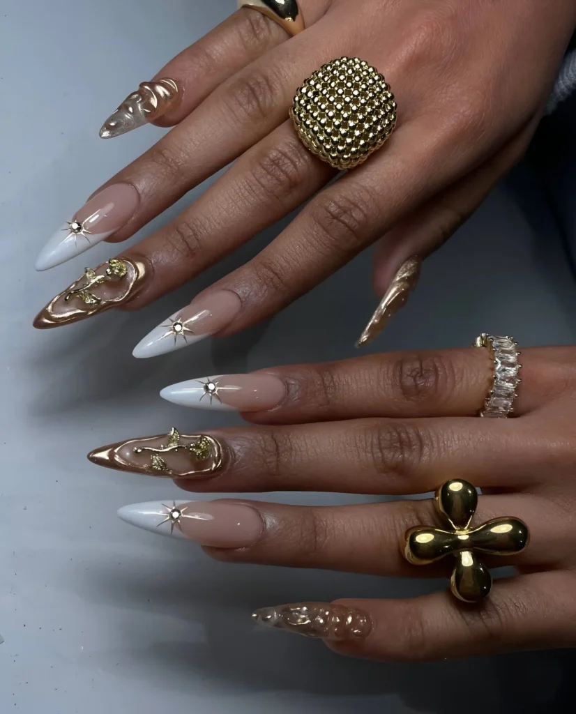 Opulent stiletto nails contrasting white V-French tips with sculptural, molten gold accents and gold vines.
