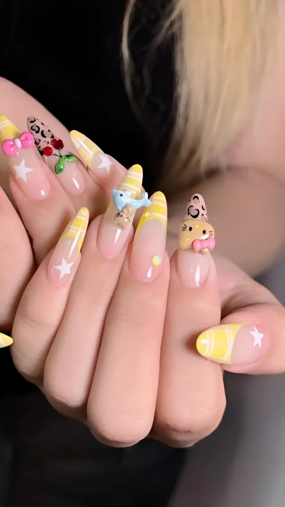 Detailed example of yellow nail ideas: Long pointed nails feature pastel yellow French tips over a sheer base, adorned with maximalist 3D charms (bow, bird, cat), plus painted stars, roses, and leopard print.