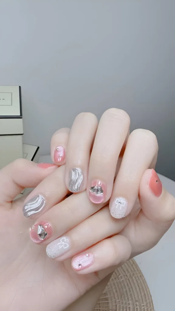 Feminine mix on short nails: sheer pink, white sugar glitter, 3D silver swirls, rhinestones, and bow accents.