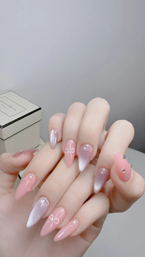 Elegant nail set combining pink polish, silver magnetic 'velvet' effect, chrome accent, bow art, and rhinestones. A stunning example of classy nail ideas.