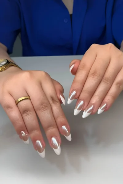 Almond nails featuring an outline French manicure with a sheer base, white tips, and a luminous pearlescent glaze on the nail bed.