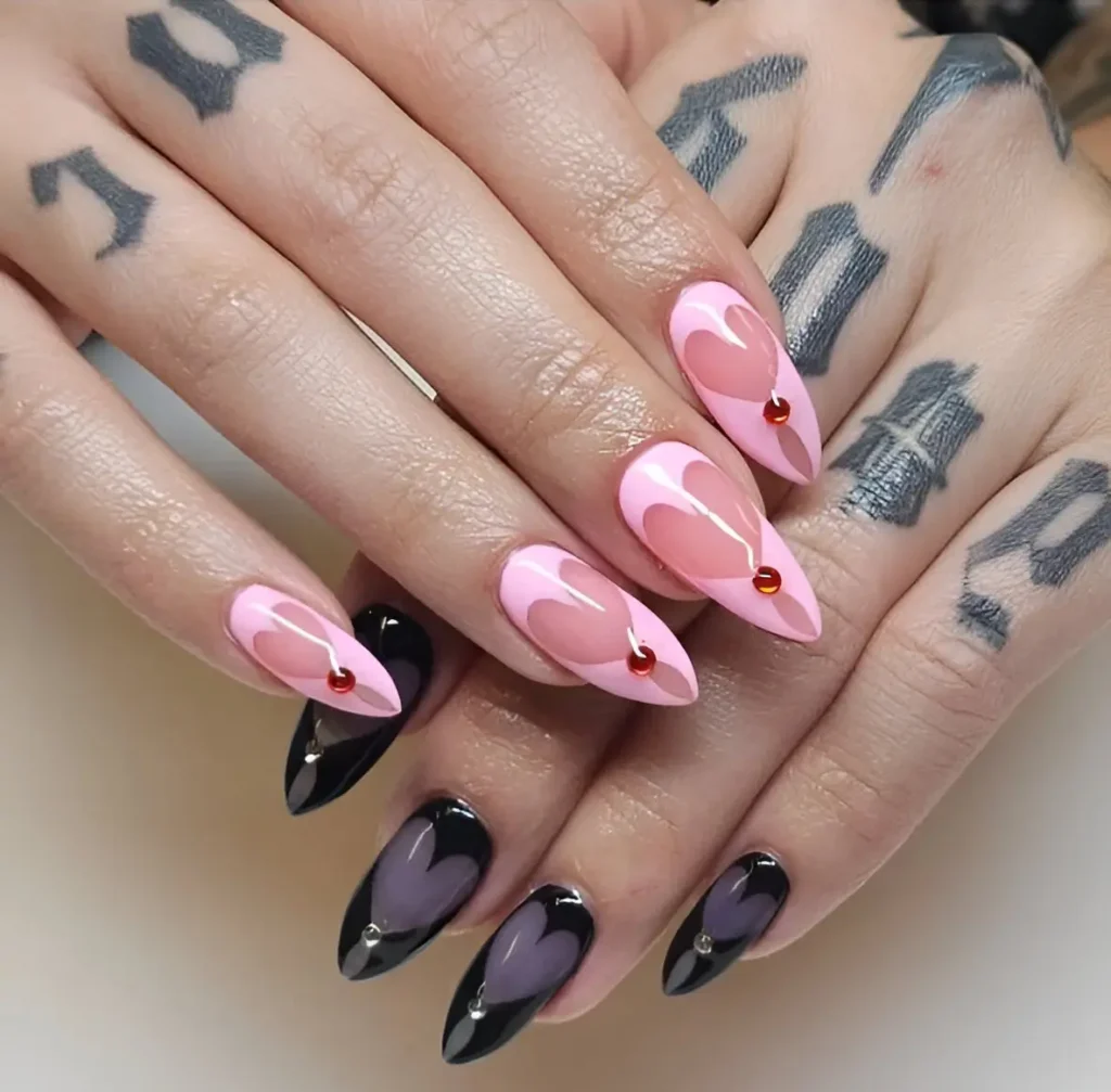 Long almond nails contrasting pink and black bases, featuring negative space hearts with inner tonal hearts and a single gem accent.