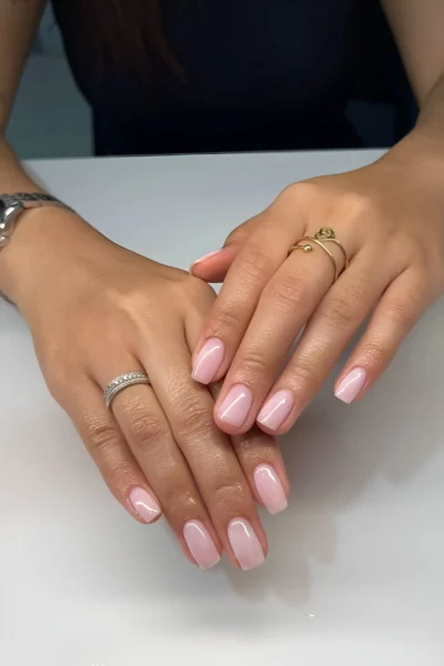 Short squoval nails painted with a semi-sheer milky pink polish for a clean, healthy look.