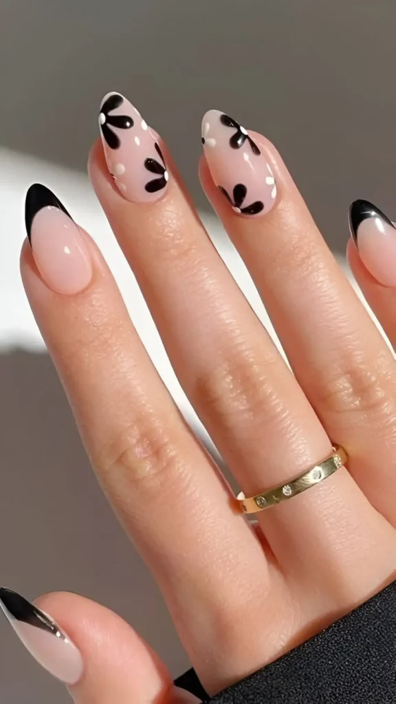 Almond nails with a mixed design: classic black French tips and sheer nails decorated with abstract black and white floral patterns.