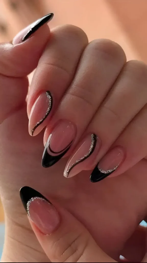 Almond nails with sheer base featuring a mix of black French tips and abstract black swirls, all outlined with fine silver glitter.