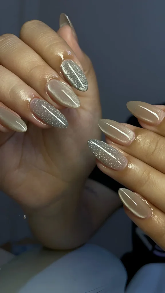 Almond nails alternating between solid creamy taupe polish and a silvery-taupe cat-eye effect polish.