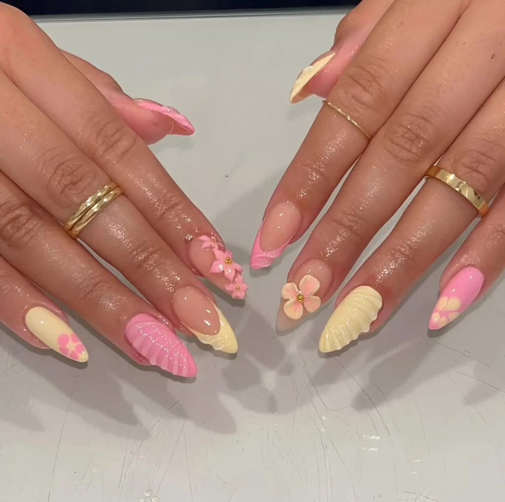 Almond nails mixing pink and yellow 3D shell textures, pink 3D flowers, pale yellow tips with tiny flowers, and pink wavy French tips.