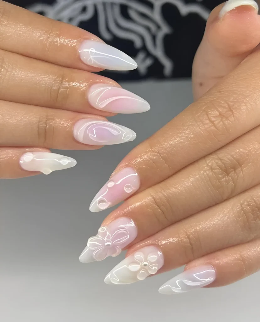 Long almond nails with sheer milky shimmer base featuring delicate white 3D flowers and fine white 3D abstract swirls.