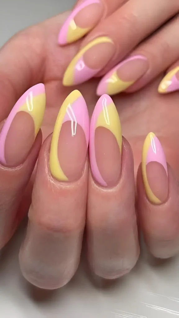 Long almond nails with curved colour blocks of pastel yellow and pastel pink, featuring a curved negative space section near the cuticle on each nail.