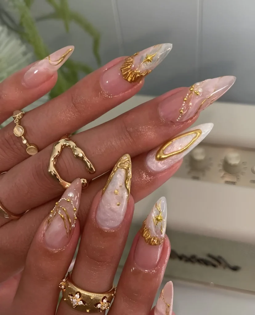 Ethereal stiletto nails with sculpted gold frames, celestial starbursts, and textured pearlescent backgrounds.