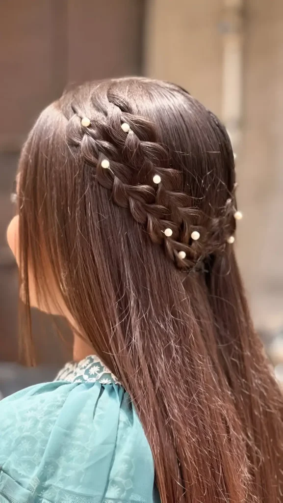 Close-up back view of long straight dark hair styled with two parallel headband braids across the crown, adorned with pearls.