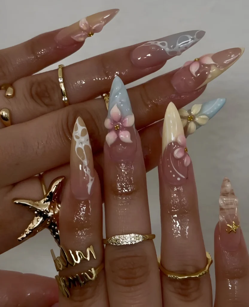 Dreamy stiletto nails featuring blooming white 'milk bath' effect, pastel bases, and delicate 3D sculpted flowers.