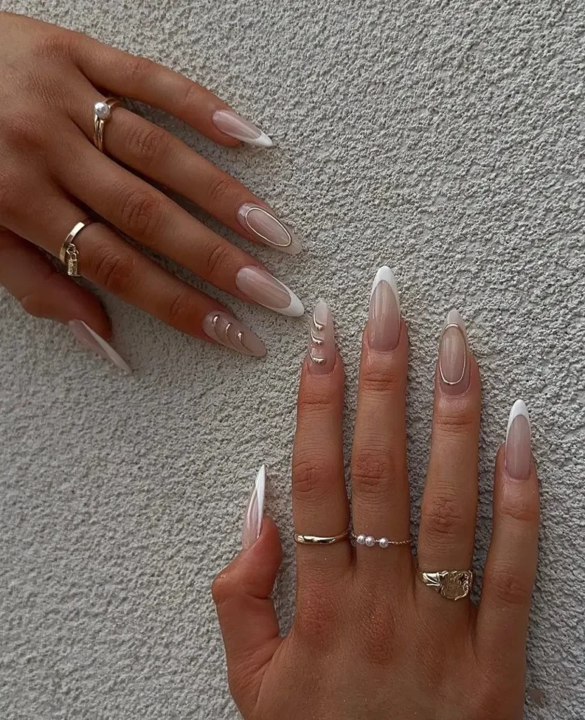 Minimalist chic French manicure with fine gold line details and a single pearl accent on long almond nails.