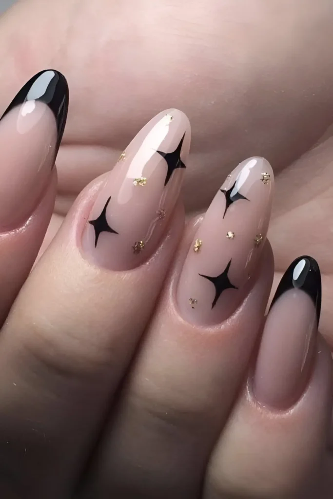 Oval nails with mixed design: classic black French tips and sheer nails decorated with black starburst graphics and scattered gold glitter specks.