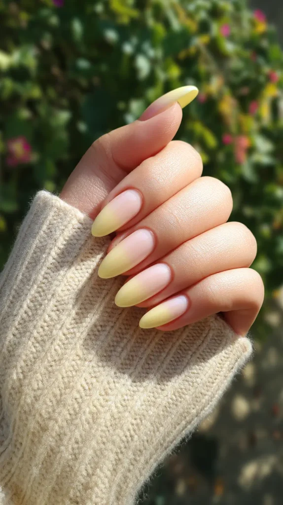 Long almond nails with a smooth ombré effect, fading from pastel yellow at the tips to a milky white/nude base near the cuticles.