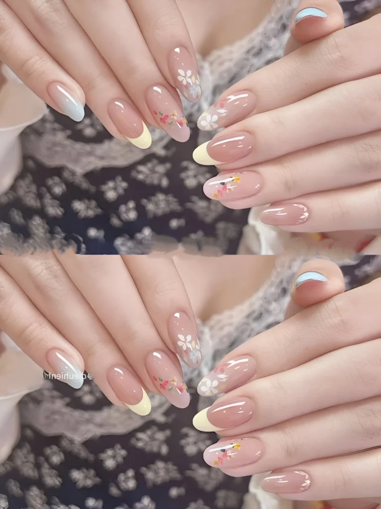 Almond nails with sheer base featuring mismatched pale yellow and hazy blue tips, and delicate painted white and colorful floral accents.