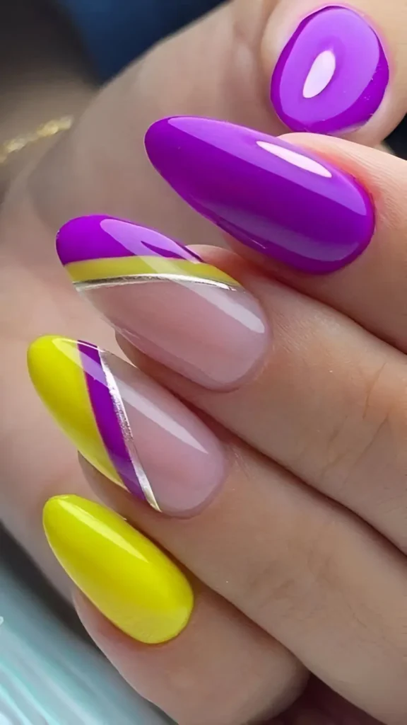 Almond nails with a mix of solid neon yellow, solid purple, and nails with geometric blocks of yellow and purple against a sheer base, separated by a thin silver line.