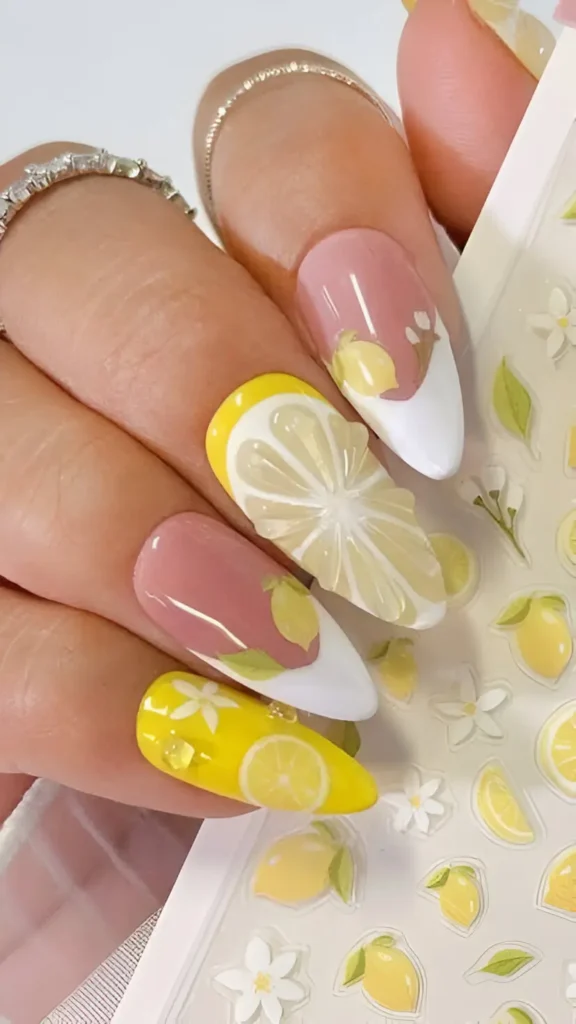 Long almond nails with a lemon theme: solid yellow nails, nails with detailed lemon slice art (possibly 3D), and nails with sheer bases, white tips, and small lemon/leaf illustrations.