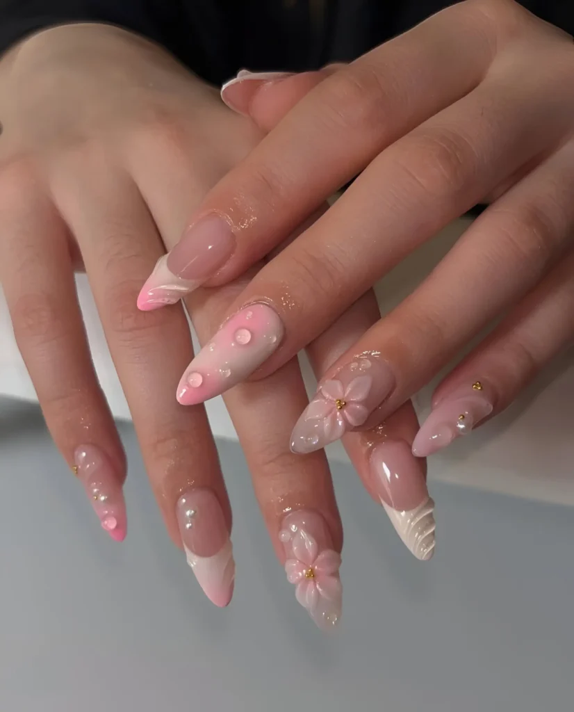 Long almond nails mixing pink ombré with 3D water droplets and pearls, textured white tips, and delicate 3D floral accents.