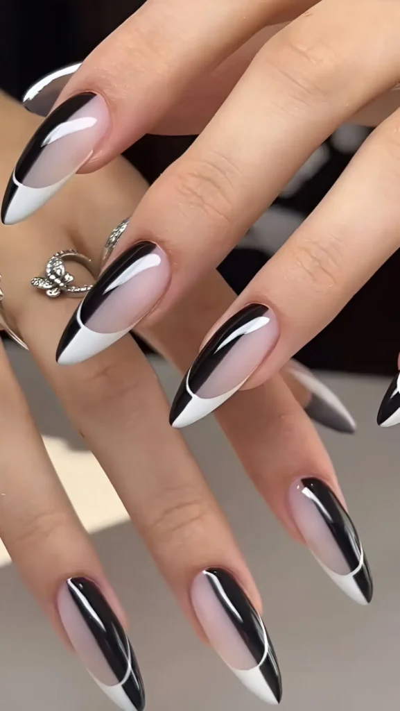 Long stiletto nails featuring a graphic black and white design with sharp white tips and curved black lines over a sheer base.