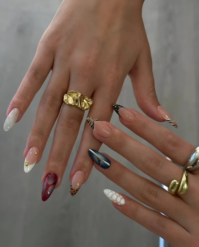 Eclectic mix-and-match manicure on almond nails featuring animal print, chrome, texture, and abstract designs.
