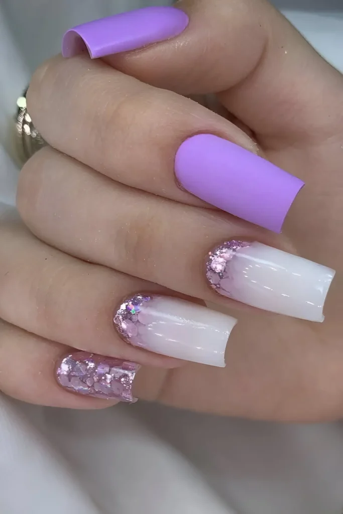 Long square nails with matte pastel lilac, sheer white base with purple glitter gradient, and full purple glitter accents.
