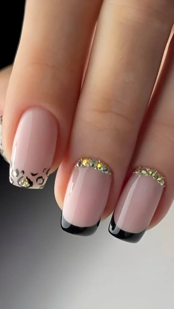 Short square nails with mixed design: black French tips and leopard print tips, both bordered by a dense line of iridescent rhinestones on the smile line.