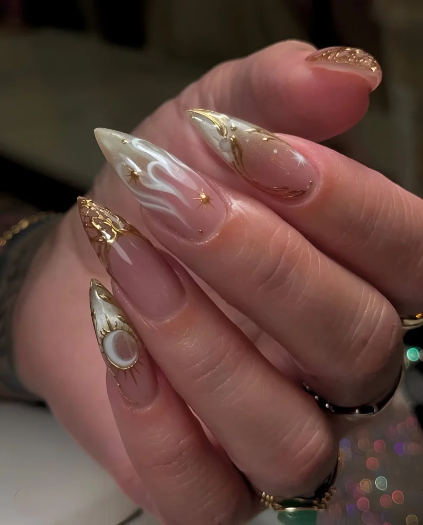 Trending opulent stiletto nail design featuring sculpted gold frames, pearly textures, and celestial motifs.
