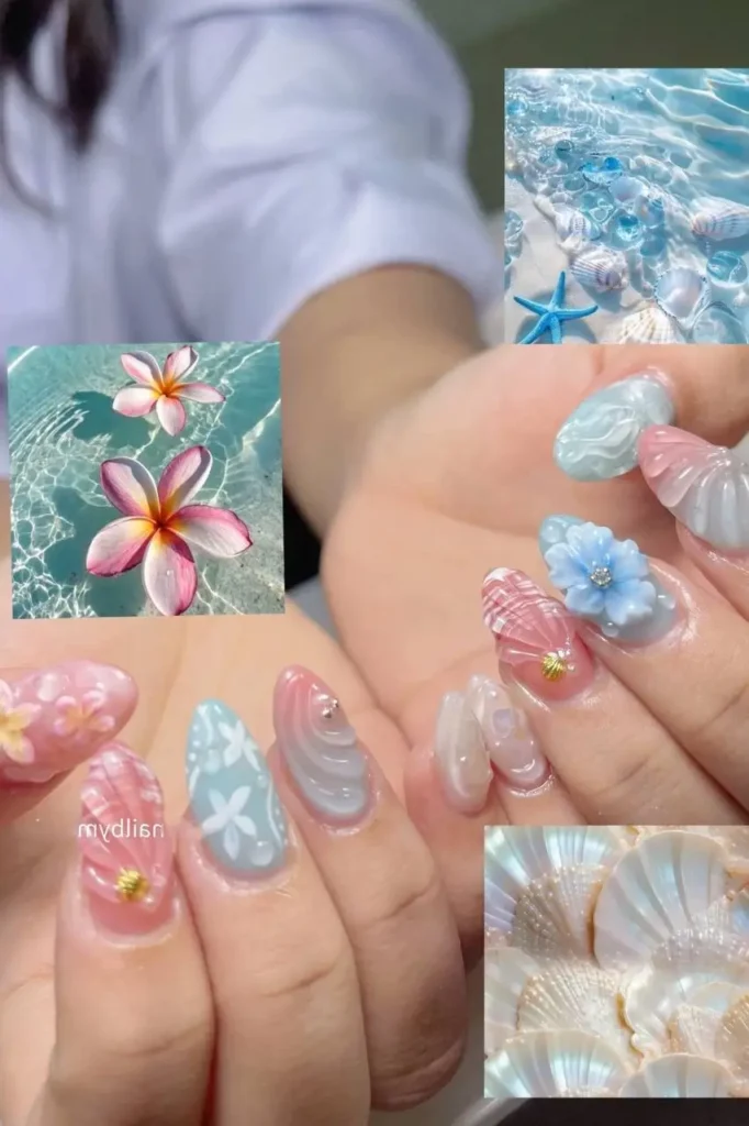 Almond summer nails with pastel blue, pink, and white mix of 3D flowers, sculpted waves/shells, and painted starfish.
