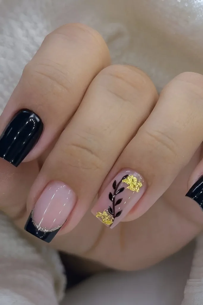 Square nails with mixed design: black French tips with glitter outline, solid black, and sheer nail with black botanical sprig and gold foil flowers.