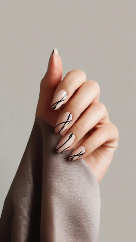 Almond-shaped nails with a sheer nude base featuring abstract, overlapping thin black line art designs.